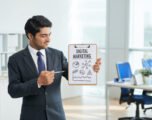 man-suit-standing-office-with-clipboard-pointing-poster-with-words